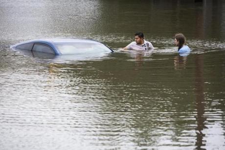 Roberto Salas, left, and Lewis Sternhagen, right, check a flooded car on the frontage road in between South Loop West Freeway and South Post Oak Road near the Willow Waterhole Bayou, Tuesday, May 26, 2015, in Houston. Floodwaters kept rising Tuesday across much of Texas as storms dumped almost another foot of rain on the Houston area, stranding hundreds of motorists and inundating the highways. (Marie D. De Jesus/Houston Chronicle via AP)

