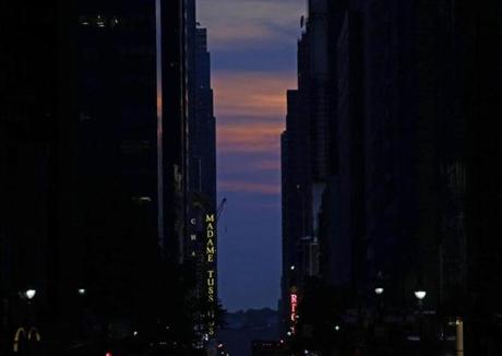 epa04774885 The sun is seen setting behind buildings on 42nd Street during the Manhattanhenge, a twice a year occurrence in which the setting sun aligns with the street grid of New York City, in Manhattan, New York , USA, 29 May 2015. This year the sun was mostly obscured by low-level clouds. EPA/PETER FOLEY
