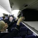 American Airlines flight attendant Renee Schexnaildre demonstrates the overhead baggage area during a media preview of the airline's new Boeing 737-800 jets in 2009.