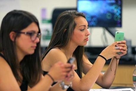 Melrose High students Beatrice Affatato (left) and Miranda Lombardo use smartphones in Blair Cochran?s physics class.

