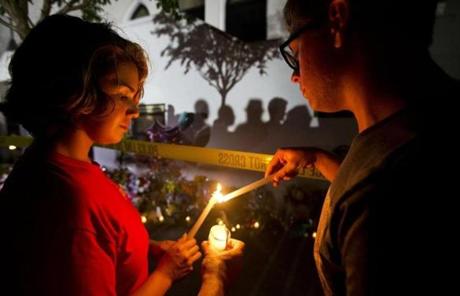 Olina Ortega, left, and Austin Gibbs lit candles Thursday at a sidewalk memorial in front of Emanuel AME Church.
