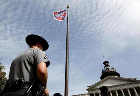 A South Carolina state trooper stood at the bottom of a Confederate flag at the base of a confederate memorial in front of the South Carolina State House in Columbia, S.C.
