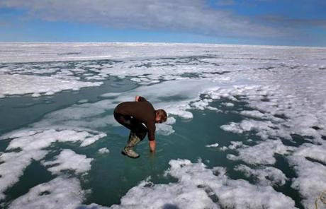 Researcher Josh Jones stood on the Arctic ice and put his arm in to see how salty the water might be at Barrow, Alaska.
