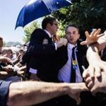 Bodyguards tried to shield Prime Minister Aleksandar Vucic (center with glasses) as members of an angry crowd threw stones at him at the Potocari Memorial Center.