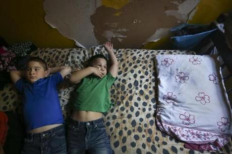 Brothers J ose and William Garcia lay on their bed inside their apartment, where paint peels from the walls.
