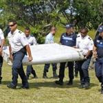 French police officers carried a piece of debris from a plane in Saint-Andre, Reunion Island.
