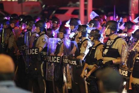 Police officers in riot gear gathered as protesters marched on the anniversary of the fatal shooting of Michael Brown.

