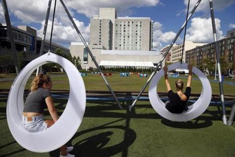 Sisters Mia, 15, (left) and Tal Ginsburg, 21, of Los Angeles were on the swings at the Lawn on D in South Boston on Wednesday. 
