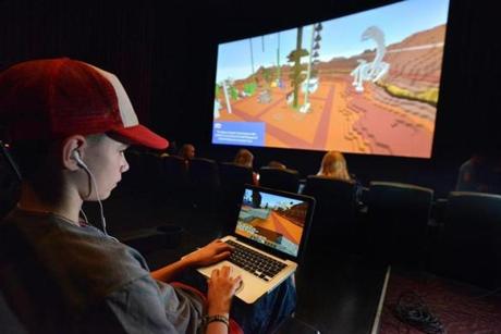Gavin Chambers, 15, of Windham, Maine, plays on his laptop while the theater screen showed another view of the action during the Super League Gaming Minecraft tournament.
