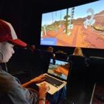 Gavin Chambers, 15, of Windham, Maine, plays on his laptop while the theater screen showed another view of the action during the Super League Gaming Minecraft tournament.