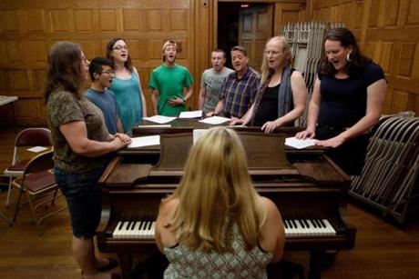 Music director Sandi Hammond plays piano for chorus members (from left) Diane Griffin, Avery Lee, Tarah Tamayo, Owen Lewis, Kit Johnson, George Hastie, Laurie Wolfe, and Samantha Magnusson. 

