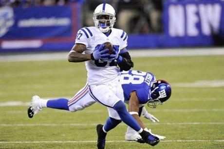 Indianapolis Colts wide receiver Reggie Wayne (87) runs away from New York Giants' Jayron Hosley (28) for a touchdown during the second half of an NFL football game Monday, Nov. 3, 2014, in East Rutherford, N.J. (AP Photo/Bill Kostroun)
