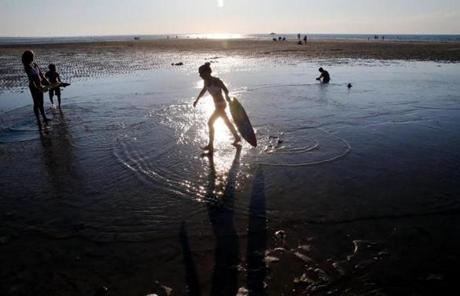 Madison Borge, 12, was silhouetted in the sun?s reflection on the water while skim boarding at Mayflower Beach on Cape Cod Bay in Dennis, where she was vacationing with her family last week.
