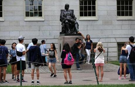 Visitors took photos by the John Harvard statue on Thursday.
