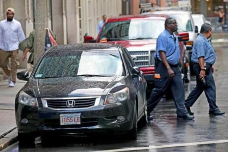 Traffic enforcement officers walked past a car parked on Water Street in late September.
