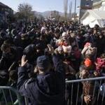 A Serbian police officer attempted to organize migrants lining up to get registered at a refugee center in the southern Serbian town of Presevo on Monday.
