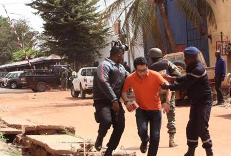 Mali trooper assist a hostage, centre, to leave the scene, from the Radisson Blu hotel to safety after gunmen attacked the hotel in Bamako, Mali, Friday, Nov. 20, 2015. Islamic extremists armed with guns and throwing grenades stormed the Radisson Blu hotel in Mali's capital Friday morning, killing at least three people and initially taking numerous hostages, authorities said. (AP Photo/Harouna Traore)
