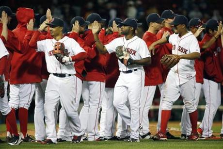 The Boston Red Sox, including, foreground from left, Mookie Betts, Jackie Bradley Jr. and Xander Bogaerts celebrate after defeating the Baltimore Orioles 8-0 in a baseball game in Boston, Saturday, Sept. 26, 2015. (AP Photo/Michael Dwyer)
