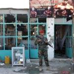 An Afghan soldier stood guard Wednesday at one of the stores burned during the Taliban attack on the air base.