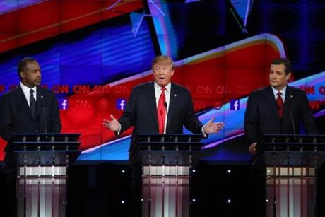 Republican presidential candidate Donald Trump (center) spoke as Ben Carson (left) and Ted Cruz (right) listened. 

