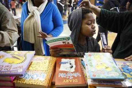 Taurean Alexander, 7, looked over books during a gift giveaway at Saint Peter's Teen Center on Christmas Eve.  
