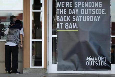 A man looked into the window of an REI store that was closed. 
