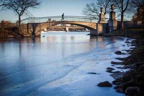 A runner crossed a bridge near a patch of ice along the Charles River Esplanade on Wednesday.
