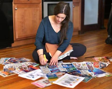 Tufts student Hannah Steinberg surrounded by the coupons she collects to buy goods to donate to charity. 
