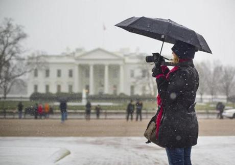 Chris Vozzo, who is visiting from Australia, stopped to photograph snow falling in front of the White House Friday. 
