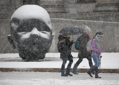 A group of people made their way past a sculpture on the grounds of the MFA as snow fell in Boston. 
