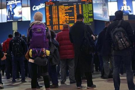 Commuters stood around a departure board in South Station on Thursday.
