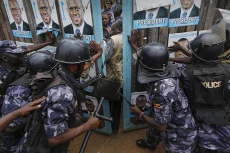 Riot police officers try to close the gate to lock supporters of Kizza Besigye, the leader of the main opposition Forum for Democratic Change (FDC) and the main opposition candidateate, inside Besigye?s party headquarters in Kampala, Uganda, Feb. 19. Ugandan police on Feb. 19 stormed Besigye?s party headquarters and arrested him. Police also fired tear gas and arrested some of his supporters who took to the streets. Preliminary result by Electoral Commission shows incumbent President Yoweri Museveni taking a lead over his main opponent.
