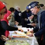 Gilane Shaker, left, of the Islamic Society of Boston Cultural Center served food to US Navy veteran David Bonner during a gathering in Boston on Saturday.