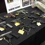 Weapons, money, and other items collected during a gang roundup were displayed after 48 members and associates of Boston's largest and most powerful gang, the Columbia Point Dawgs, were indicted on drug and gun charges in June 2015.