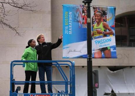 Boston- 03/18/2016- Mayor Marty Walsh joined defending Women's Boston Marathon champion Caroline Rotich and Bill Rodgers to reveal the 2016 Boston Marathon Banners on Boylston Street at the finish line. Rotich and Rodgres on a lift with the new banner.Boston Globe staff photo by John Tlumacki (metro)
