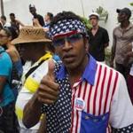 A man wearing a shirt and head scarf with a Stars and Stripes motif flashes a thumbs up at a weekly rumba dance gathering in Havana, Cuba, on Saturday.