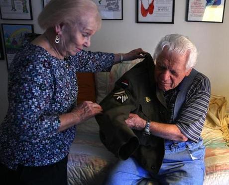 Ruth Bier helped her husband, Ghost Army veteran Bud Bier, don his Eisenhower jacket in their home in Dartmouth.
