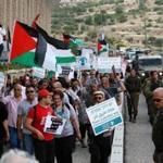 Peace activists hold placards during a joint Israeli-Palestinian peace march along the Israeli controversial separation wall in the West Bank city of Beit Jala between Bethlehem and Jerusalem on Friday.