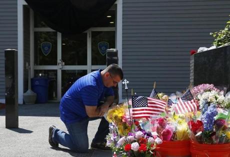 Howard Bregman kneeled beside a growing memorial for Auburn Police Officer Ronald Tarentino Jr. Monday. 
