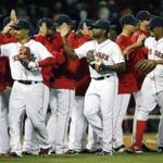 The Boston Red Sox, including, foreground from left, Mookie Betts, Jackie Bradley Jr. and Xander Bogaerts celebrate after defeating the Baltimore Orioles 8-0 in a baseball game in Boston, Saturday, Sept. 26, 2015. (AP Photo/Michael Dwyer)