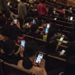 Members of the audience on their cell phones before the start of a show at the National Center for the Performing Arts in Beijing, March 6, 2016. Theaters and other venues have adopted what they say is an effective â?? others might say disturbing â?? solution called laser shaming: aiming light beams at patrons to discourage them from using cellphones during shows. (Gilles Sabrie/The New York Times)