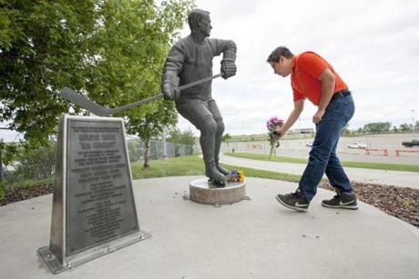Matt Adamowski lays flowers at a statue of Gordie Howe at the Sasktel Centre in Saskatoon, Saskatchewan, Friday, June 10, 2016. Gordie Howe, the hockey great who set scoring records that stood for decades, has died. He was 88. Son Murray Howe confirmed the death Friday, June 10, 2016, texting to The Associated Press: 