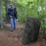 Mike Ryan, former executive director of the Friends of the Middlesex Fells Reservation, examined a mysterious stone marker on the island in Stoneham pond. 