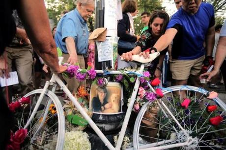 Mourners reach out to touch a ghost bike at a vigil for Amanda Phillips, who was killed while riding a bike in Inman Square by inattentive drivers.

