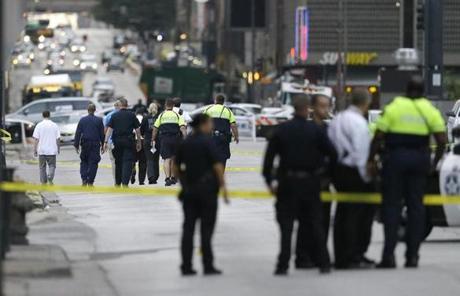 Investigators walk the scene of a shooting in downtown Dallas, Friday, July 8, 2016. Snipers opened fire on police officers in the heart of Dallas during protests over two recent fatal police shootings of black men. (AP Photo/LM Otero)

