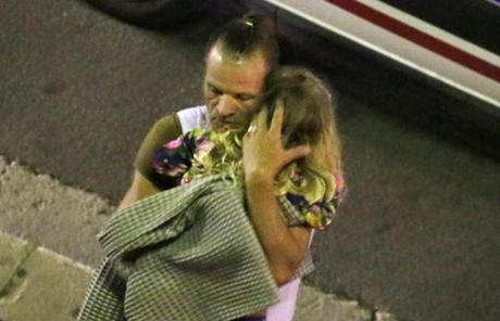 FRANCE SLIDER2 A man holds a child after a truck plowed through Bastille Day revelers in the French resort city of Nice, France, Thursday, July 14, 2016. France was ravaged by its third attack in two years when a large white truck mowed through revelers gathered for Bastille Day fireworks in Nice, killing at dozens of people as it bore down on the crowd for more than a mile along the Riviera city's famed seaside promenade. (Sasha Goldsmith via AP)
