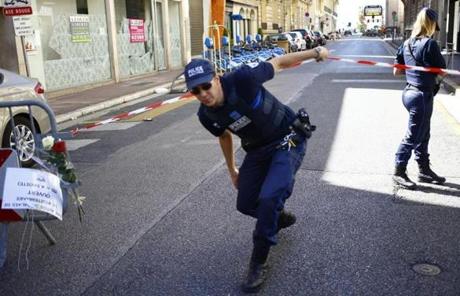 FRANCE SLIDER2 A police officer walks under the cordon at the scene after a truck attack in Nice, southern France, Friday, July 15, 2016. A large truck mowed through revelers gathered for Bastille Day fireworks in Nice, killing more than 80 people and sending people fleeing into the sea as it bore down for more than a mile along the Riviera city's famed waterfront promenade. (AP Photo/Francois Mori)
