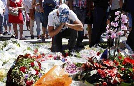 FRANCE SLIDER2 A man reacts near bouquets of flowers as people pay tribute near the scene where a truck ran into a crowd at high speed killing scores and injuring more who were celebrating the Bastille Day national holiday, in Nice, France, July 15, 2016. REUTERS/Pascal Rossignol
