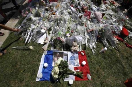 Family pictures are seen on a French flag near tributes of flowers two days after an attack by the driver of a heavy truck who ran into a crowd on Bastille Day killing scores and injuring as many on the Promenade des Anglais, in Nice, France, July 16, 2016. . REUTERS/Eric Gaillard
