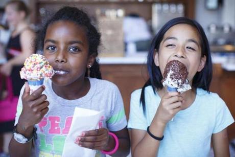 At Forge Ice Cream Bar, Lettie Carswell, 8, of Arlington enjoy a cone of strawberry with rainbow sprinkles and Clara Mapel, 8, of Cambridge a mint cookie and cream cone with chocolate sprinkles.
